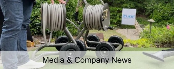 Person displaying hose reel carts with 'Eley' signing in a garden, text at bottom reads 'Media & Company News'