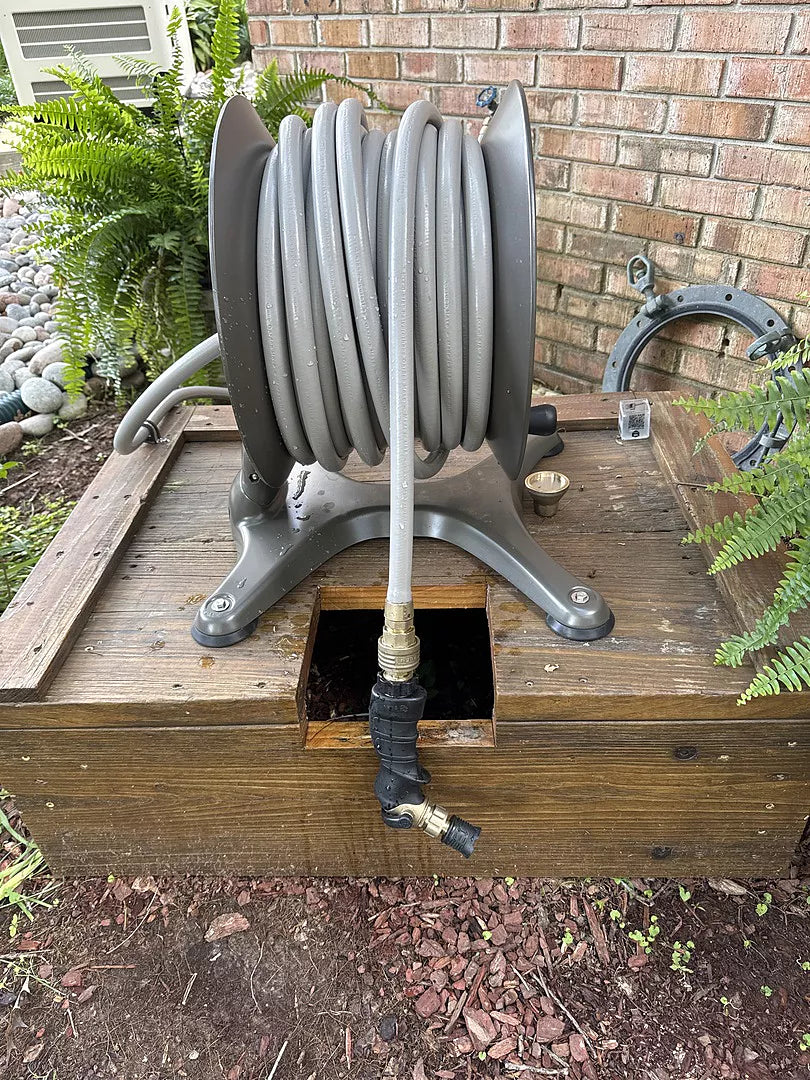 ELEY aluminum free-standing hose reel installed on a raised wood garden platform.