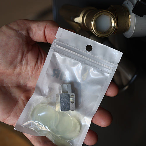 Hand holding a clear plastic bag with small replacement components for the swivel gasket repair kit against an ELEY hose reel and the 4291 swivel