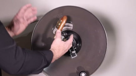 person's arms demonstrating in front of a wall mounted hose reel